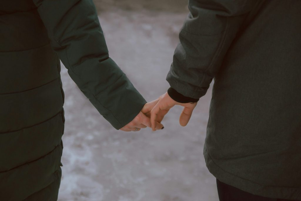 Couple holding hands with distance between them, symbolizing emotional disconnect in a cheating spouse relationship
